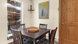 Un comedor con una mesa y sillas de madera, un cuadro en la pared y una puerta de madera.