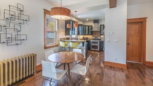 Una cocina moderna con armarios oscuros, una isla central y un comedor con una mesa redonda y sillas blancas.