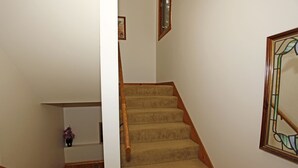 A carpeted staircase with wooden handrails, a small shelf with a vase, and a stained glass window on the right. - Next to Ouray Hot Springs | Walk to Main Street | Deck (Ouray)