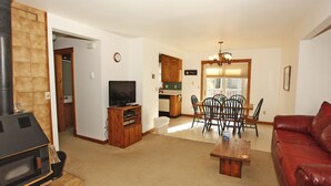 A living room with a fireplace, a television, a dining area with chairs, and a red leather couch. - Next to Ouray Hot Springs | Walk to Main Street | Deck (Ouray)