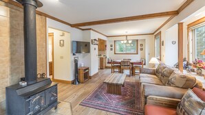 Ein Wohnzimmer mit Kamin, Holzmöbeln, Essbereich und Küche.
