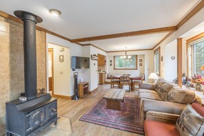 A living room with a fireplace, wooden furniture, a dining area, and a kitchen.