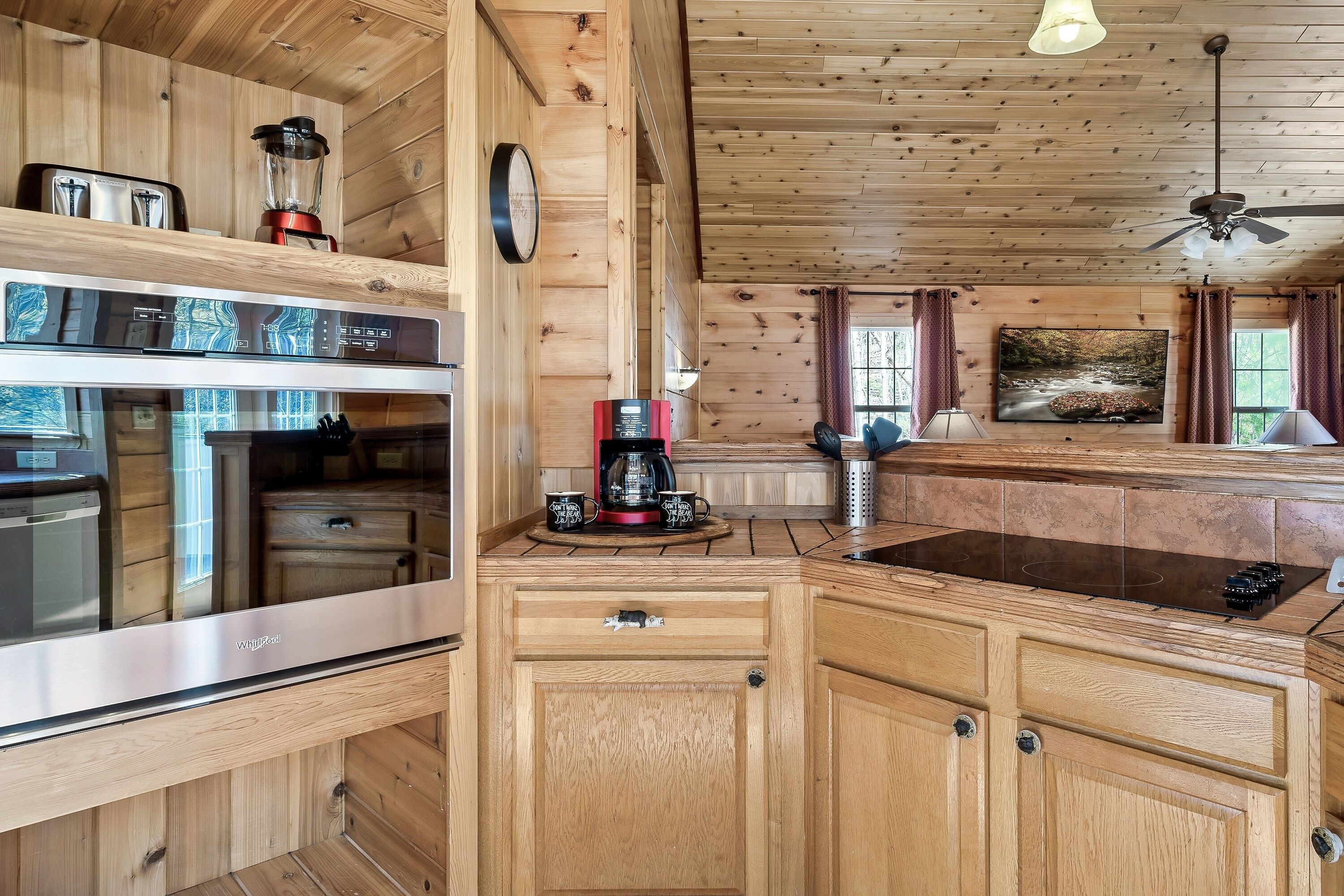 A wooden cabin kitchen with a built-in stove, a coffee maker, and a blender on the counter.