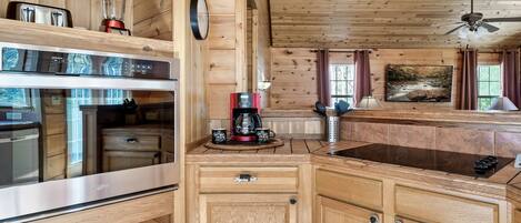 A wooden cabin kitchen with a built-in stove, a coffee maker, and a blender on the counter.