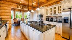 A spacious kitchen with a large island, white cabinetry, stainless steel appliances, and a wooden ceiling. - Legend- A Legendary Waterfront Stay in Ellijay, GA (Ellijay)