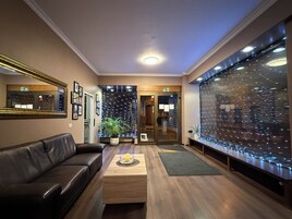 Un hall con un sofá de cuero, una mesa de centro de madera y un amplio ventanal con luces colgantes.