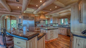 Una cocina amplia con armarios de madera, una isla grande y un refrigerador de acero inoxidable.
