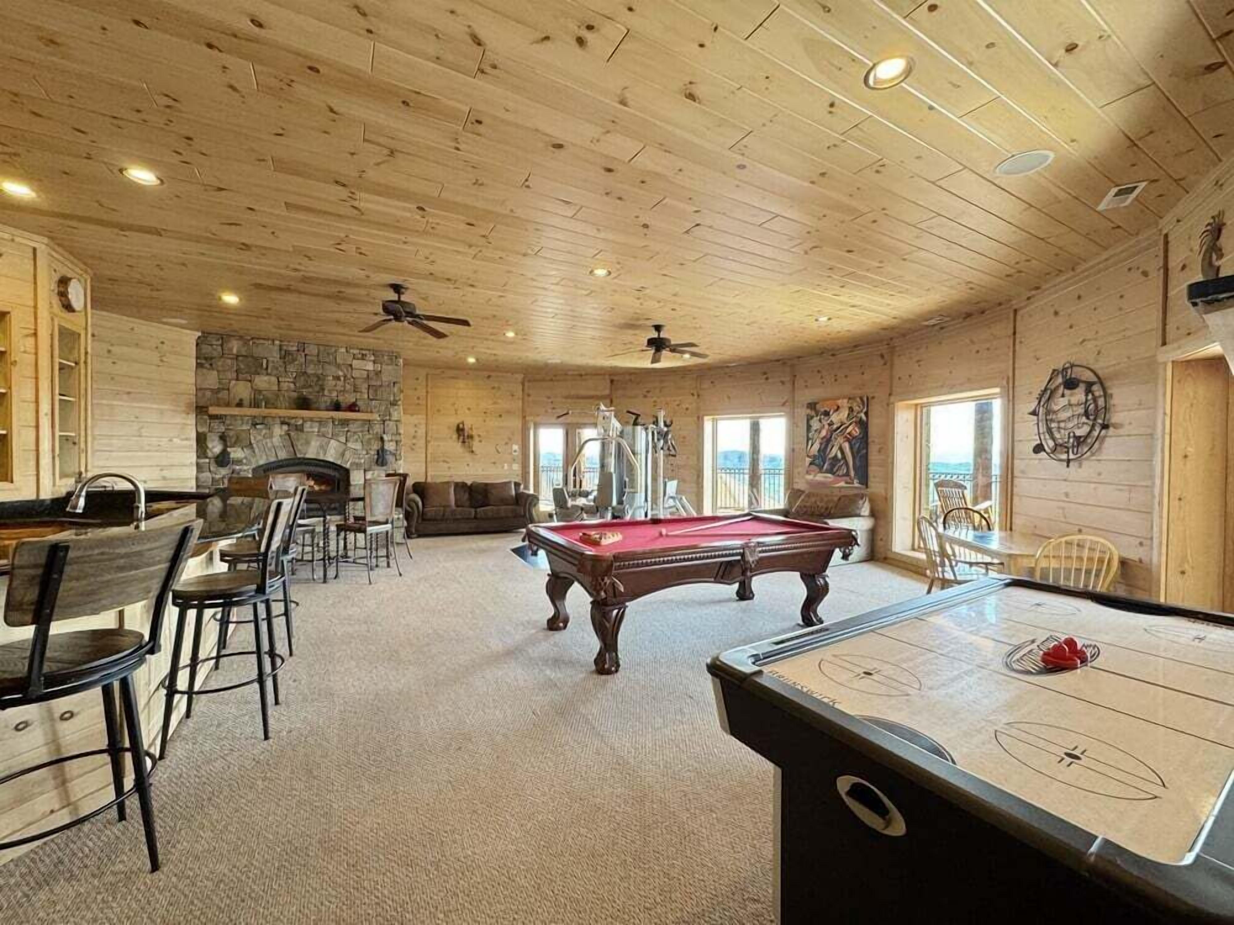 Ein Zimmer mit Billardtisch, Kamin und Steinwand.