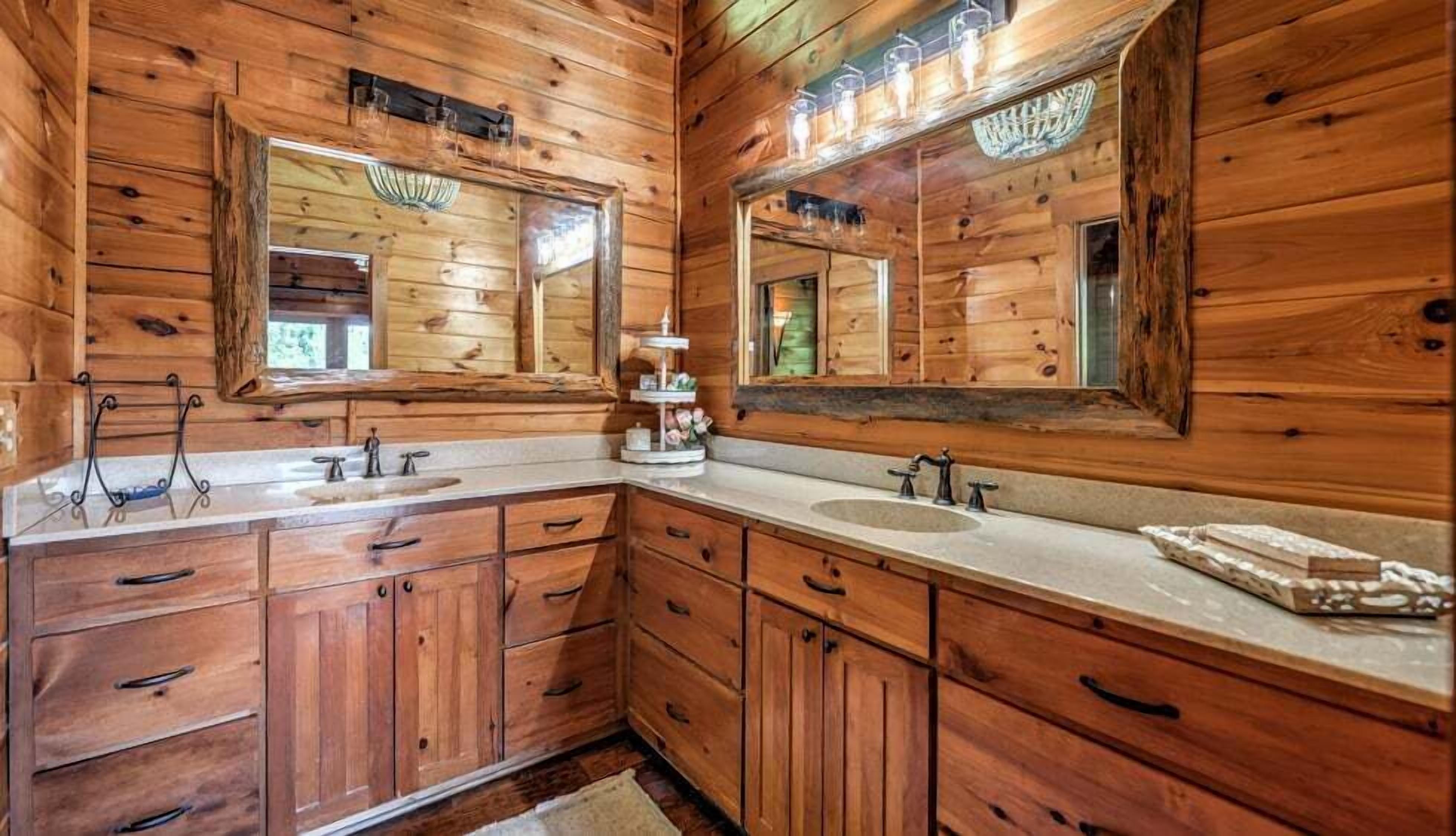 A wooden cabin bathroom with two sinks, a vanity, and a large mirror.