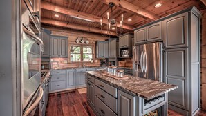 A modern kitchen with granite countertops, stainless steel appliances, and wooden cabinetry.