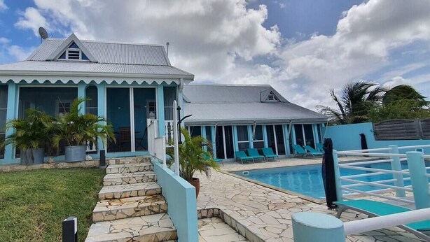 A two-story building with a pool and lounge chairs. - Résidence Aigue Marine Sainte Anne - Maison Corail (Sainte-Anne)