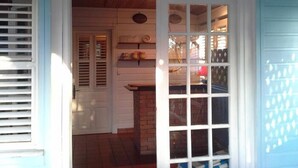 A room with a brick fireplace, a wooden ceiling, and a window with blinds. - Résidence Aigue Marine Sainte Anne - Maison Corail (Sainte-Anne)