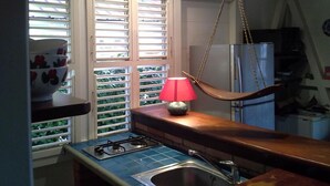 A kitchen with a gas stove, a sink, and a hanging lamp. - Résidence Aigue Marine Sainte Anne - Maison Corail (Sainte-Anne)