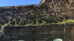 A set of ornate metal chairs and a table with a bottle and glasses on it, set against a stone wall with greenery growing over it. - Teesdale holiday cottage, sleeps 4 + dog at Bank Top, Mickleton, Barnard Castle (Mickleton)