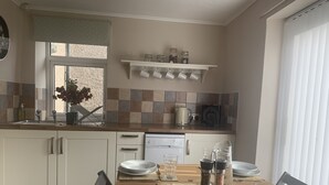 A kitchen with a dining table set for four, a coffee maker, and a salt and pepper shaker on the counter. - Teesdale holiday cottage, sleeps 4 + dog at Bank Top, Mickleton, Barnard Castle (Mickleton)