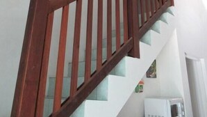 Uma escada de madeira com uma parede branca e um micro-ondas no patamar.