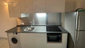 Uma cozinha compacta com máquina de lavar embutida, micro-ondas e frigorífico.