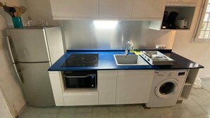 Eine kompakte Küche mit integriertem Mikrowellenherd, Backofen und Waschmaschine.