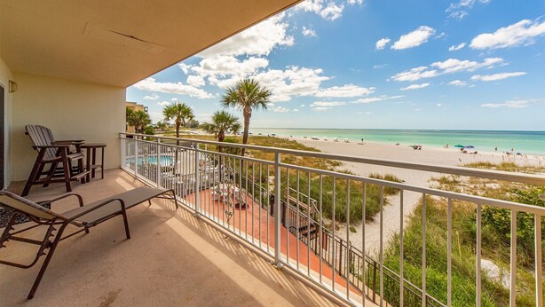 A balcony with a view of a beach and pool area. - Beachfront Condo Across from John's Pass -Madeira Norte- Gorgeous sunset views! (Madeira Beach)