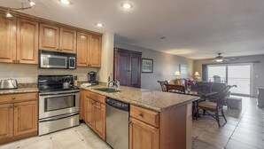 A modern kitchen with stainless steel appliances, wooden cabinetry, and a granite countertop. - Beachfront Condo Across from John's Pass -Madeira Norte- Gorgeous sunset views! (Madeira Beach)