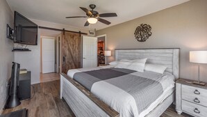 A bedroom with a bed, a ceiling fan, a TV, a desk, and a chair. - Beachfront Condo Across from John's Pass -Madeira Norte- Gorgeous sunset views! (Madeira Beach)