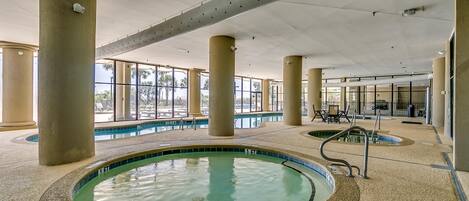 An indoor swimming pool with clear water, surrounded by beige pillars and a tiled floor.