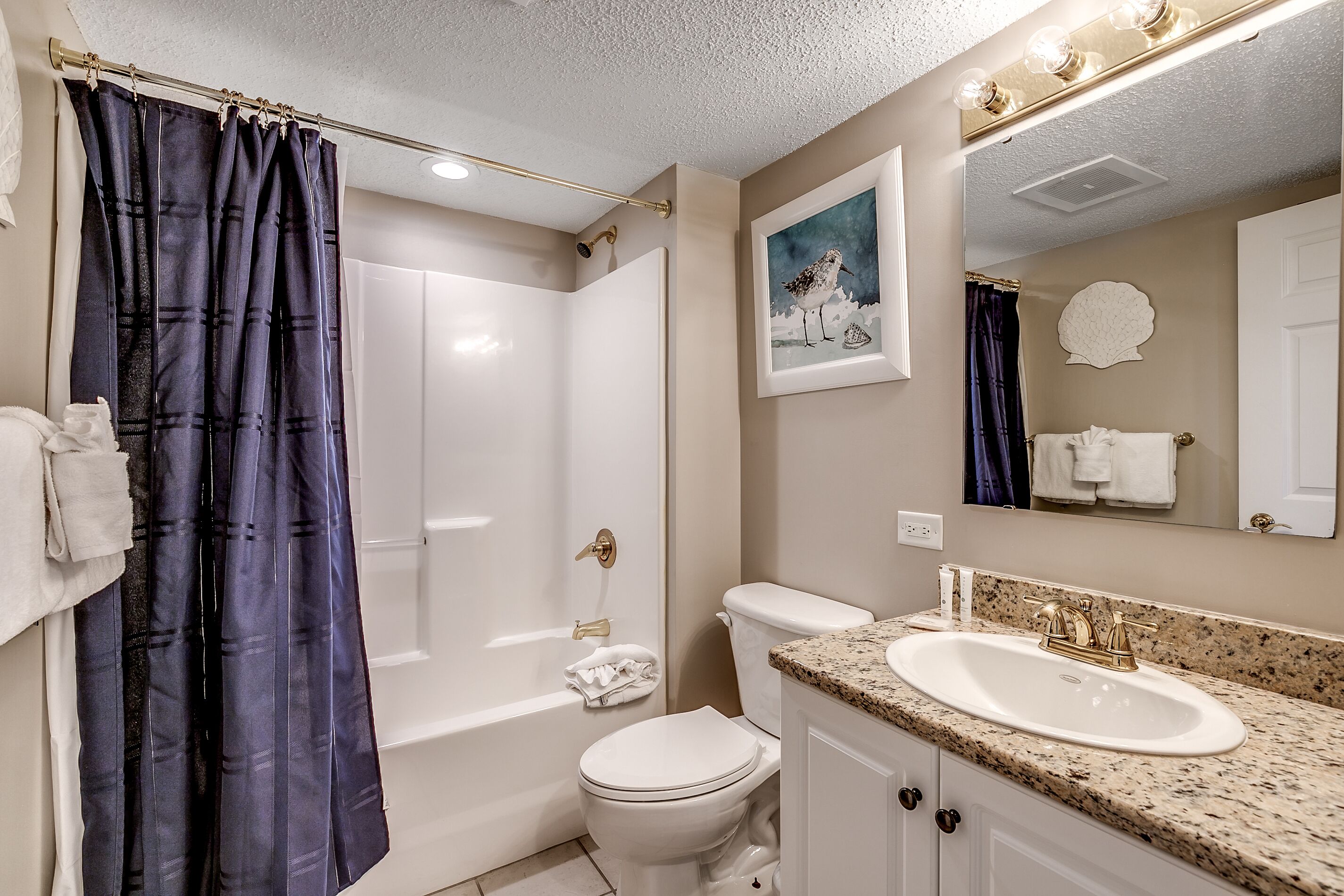A bathroom with a shower, toilet, sink, and a mirror.