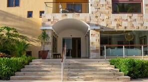 A hotel entrance with a stone facade, a balcony, and a staircase leading to the entrance. - Beautiful oceanfront apartment, 1 block from 5th Av. (Playa del Carmen)