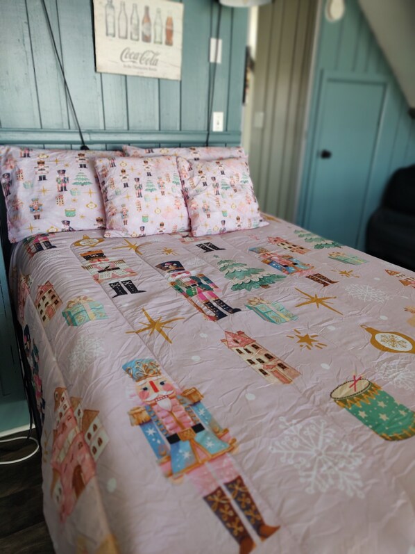 Una cama con un colcha colorida con varios diseños y una pared con un cartel de Coca-Cola.