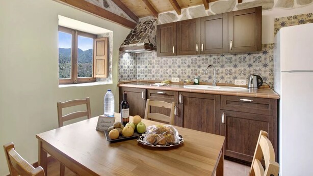 Una cocina rústica con armarios de madera, una pared de piedra y una ventana con vistas a un paisaje montañoso.