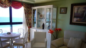 A living room with a white sofa, a glass coffee table, a white armchair, a dining table with white chairs, and a cabinet with glass doors. - SANTA MARGARITA (ESTUDIO) (Benidorm)