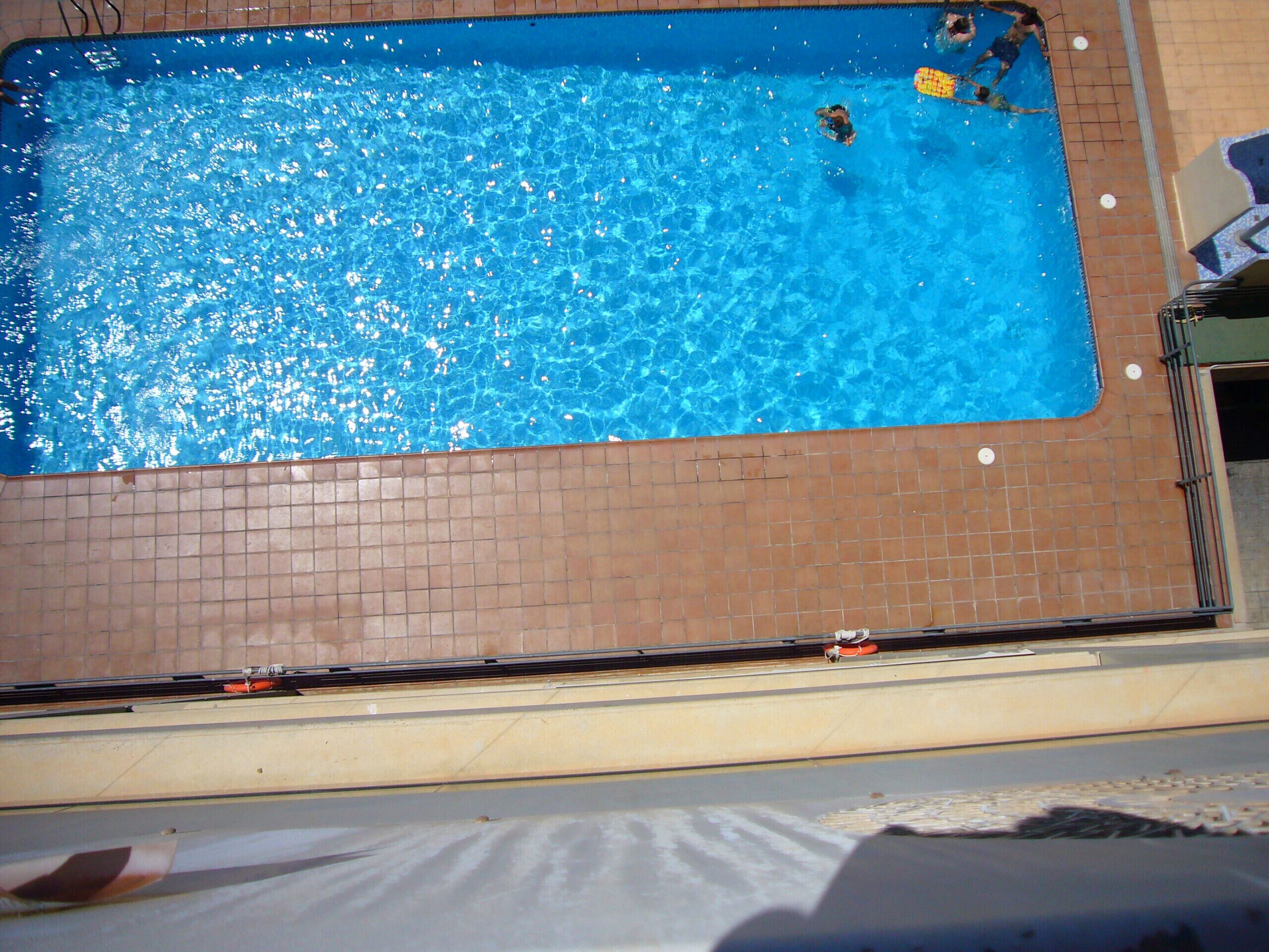 A rectangular swimming pool with a tiled edge and a tiled floor around it.