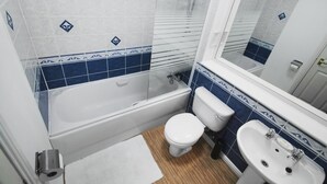 Une salle de bain équipée d’une baignoire, de toilettes, d’un lavabo et d’un miroir.