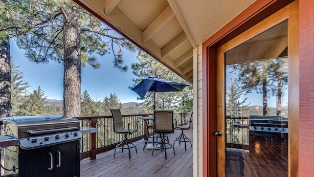 Une terrasse extérieure équipée d’un barbecue, de chaises et d’un parasol.