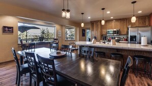 Une cuisine moderne avec des meubles en bois, des appareils en acier inoxydable et un grand îlot central doté de tabourets de bar.