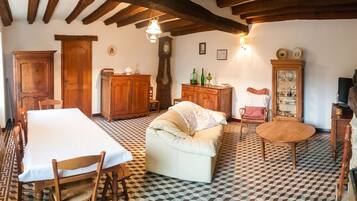 A cozy room with a checkered floor, a sofa, a dining table, wooden cabinets, and a fireplace.