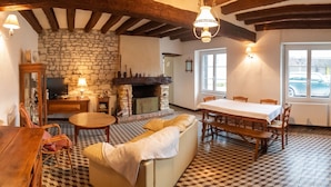 Une pièce chaleureuse avec une cheminée en pierre, des meubles en bois, une table à manger et un téléviseur.