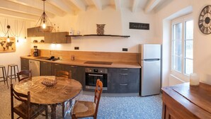Une cuisine moderne avec une table de salle à manger ronde, des chaises en bois, un four encastré et un réfrigérateur.