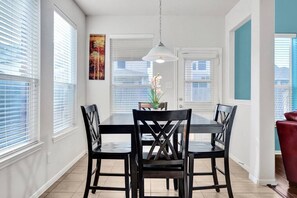 A dining area with a rectangular table and four chairs, white walls, and a hanging pendant light. - 5 BDRM, Peloton Workout station & Xbox in game RM (Montgomery County)