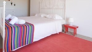 Een slaapkamer met een wit bed, een rood tapijt en een houten plafond.