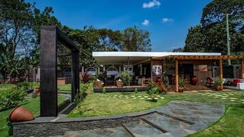 A modern outdoor patio area with a stone pathway, seating, and a covered seating area.