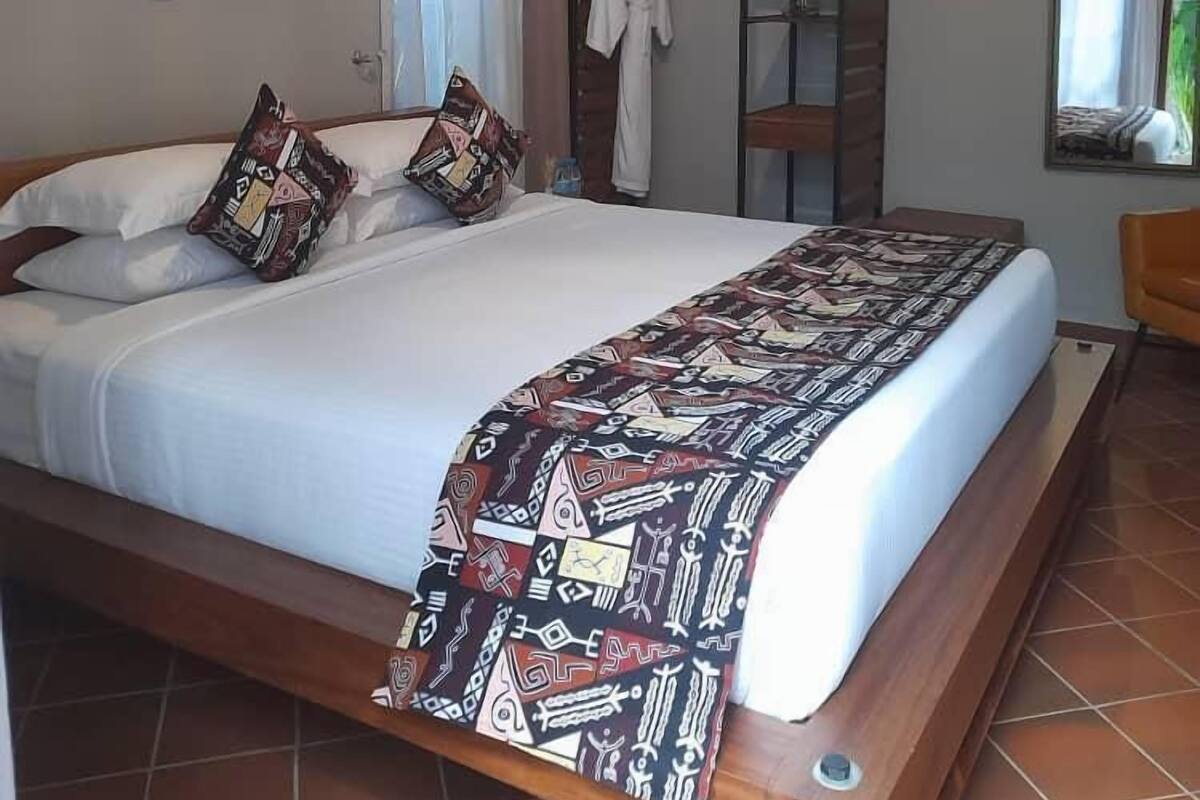 A bedroom with a bed, pillows, a patterned bedspread, a wardrobe, and wall decorations.
