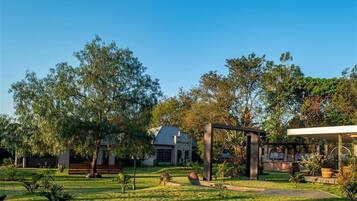 Un jardín bien cuidado con un pabellón, una casa con techo inclinado y un cielo azul despejado.
