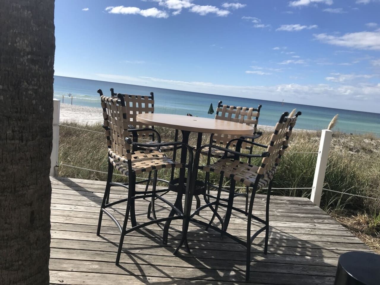 A wooden deck with a table and chairs overlooking a beach.