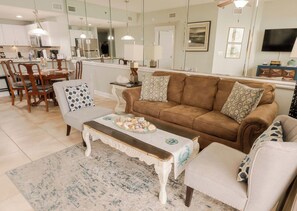 A living room with a brown sofa, a white armchair, and a coffee table with decorative items.