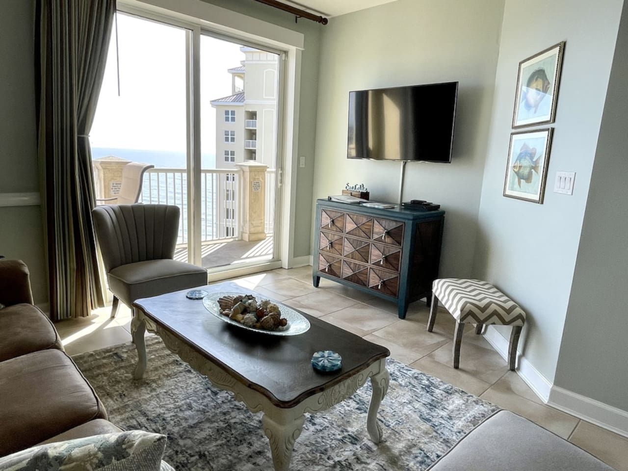 Een woonkamer met een bank, een bijzettafeltje met een decoratieve schaal, een televisie, een kast en een bankje.