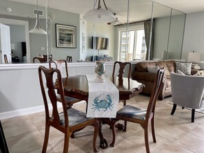 A dining area with a table covered by a tablecloth, surrounded by wooden chairs with cushioned seats. - Wake Up to Gulf Views at Sea LaVie / Sleeps 8, Heated Pools & Beach Days Await (Panama City Beach)