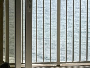 A view through a window with vertical blinds, overlooking a body of water. - Wake Up to Gulf Views at Sea LaVie / Sleeps 8, Heated Pools & Beach Days Await (Panama City Beach)