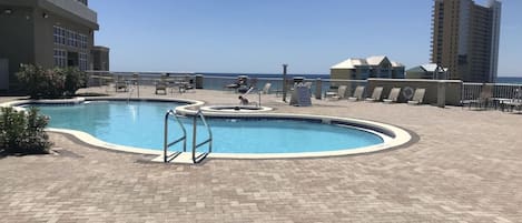 Une piscine de forme circulaire, entourée d’une terrasse en briques.