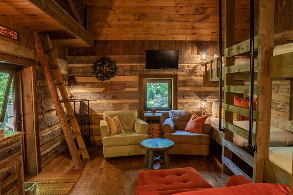 Cozy cabin-style room with a flat-screen TV, comfortable seating area, and a small table.